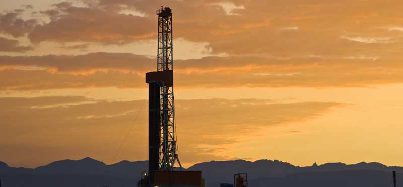 A drilling rig in Wyoming with a sunset in the background.