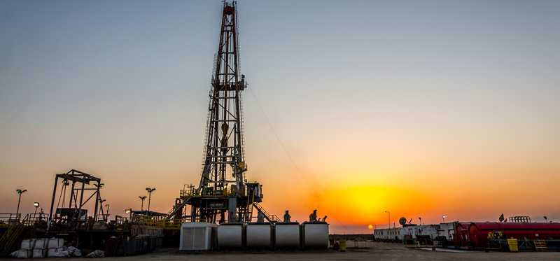 A drilling rig with the sun setting in the background.
