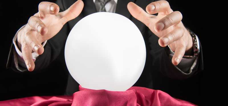 A person's hands poised over a crystal ball.