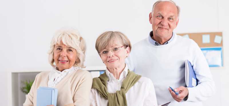 Three people with clipboards and notebooks in hand who appear intent on learning.