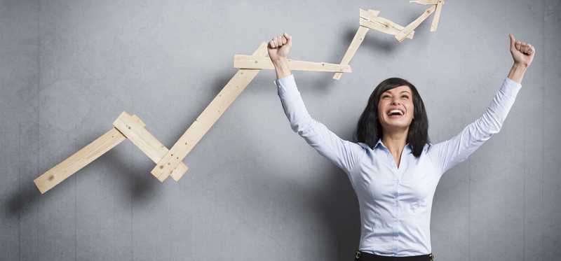 A happy business woman cheers in front of a rising chart.