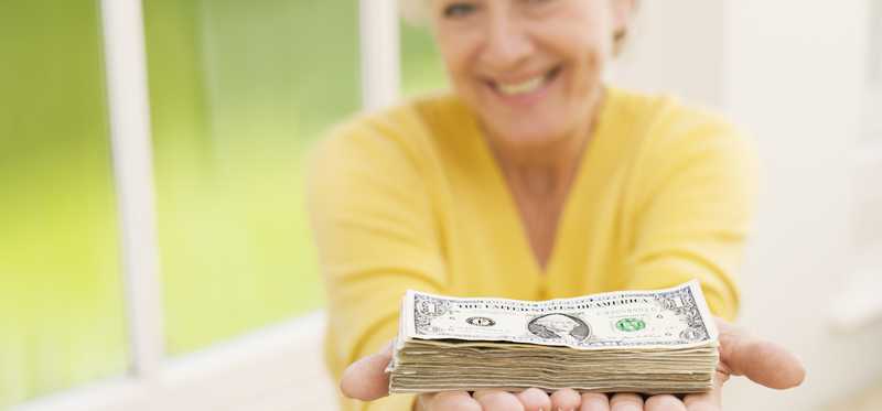 A person holding a neat stack of cash bills in outstretched hands.