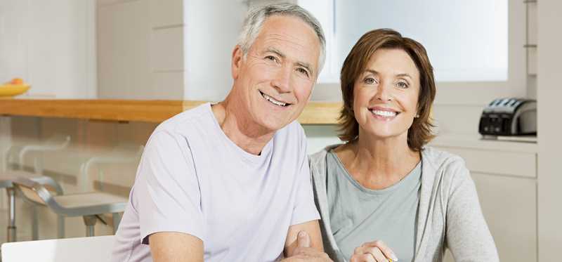 Two people smiling as they work on their finances.