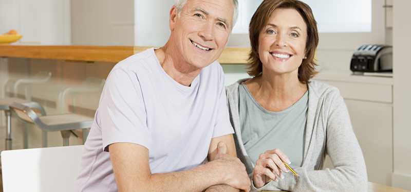 A married senior couple smiling as they work on their finances.