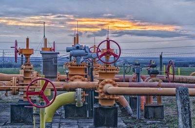 A natural gas field with pipeline valves and the sun setting in the background.
