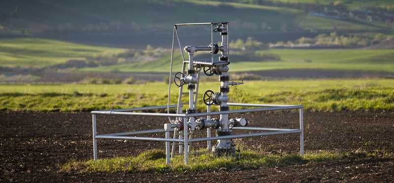 A natural gas wellhead in the middle of a field.