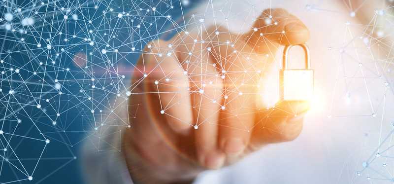 A person holding a glowing lock that surrounded by digital latticework representative of blockchain.