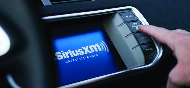A person interacting with the Sirius XM in-dash audio display.