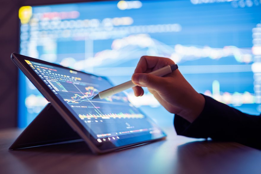 A person using a pen to point at a stock chart on a tablet.