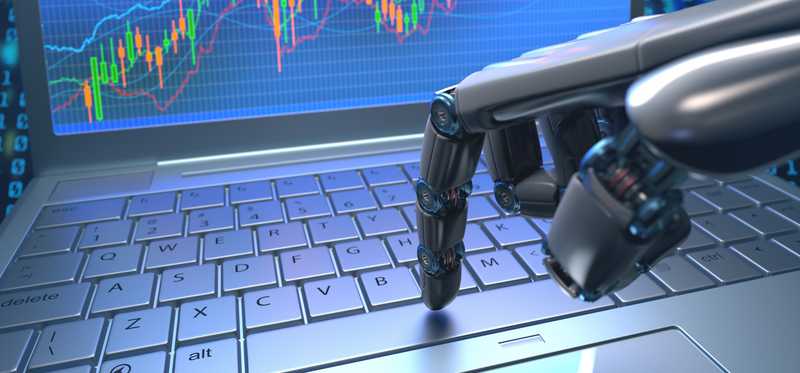 A robot's hand pressing a key on laptop that has rising stock charts on its screen.