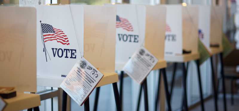 A row of U.S. polling stations with attached pamphlets.