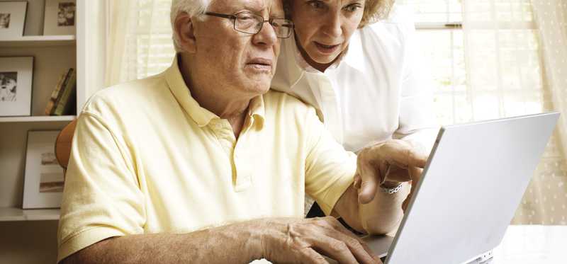 A senior couple engaging with material they're reading on their laptop.