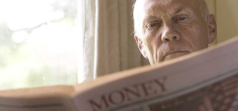 A person reading the money section of a newspaper.