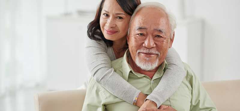 Two people smile while embracing at home.