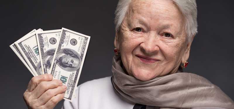 Person holding up a fanned stack of hundred dollar bills.