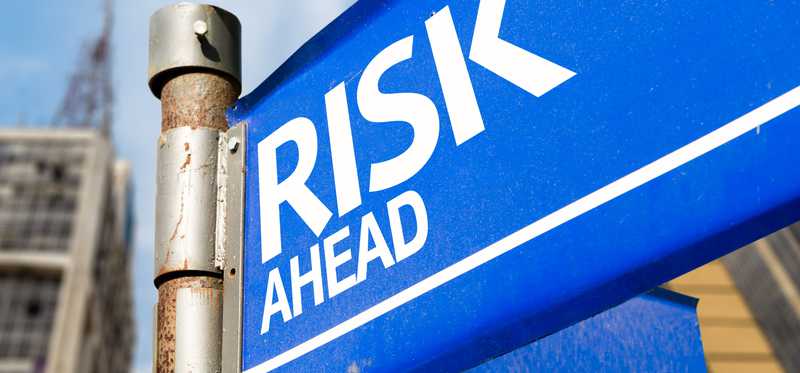 A blue corner street sign that reads risk ahead.