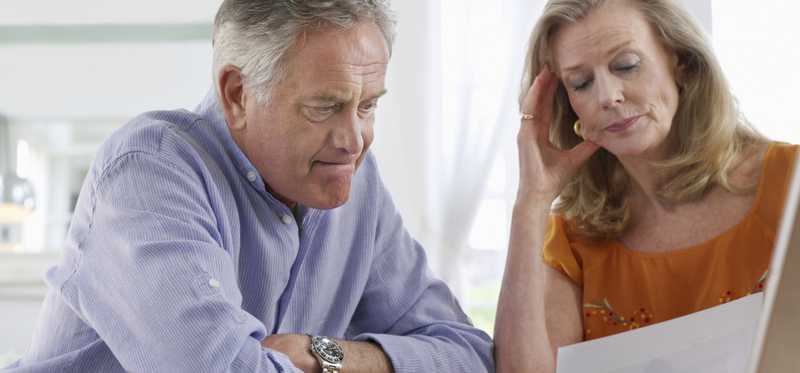 A visibly worried mature couple examining their finances.