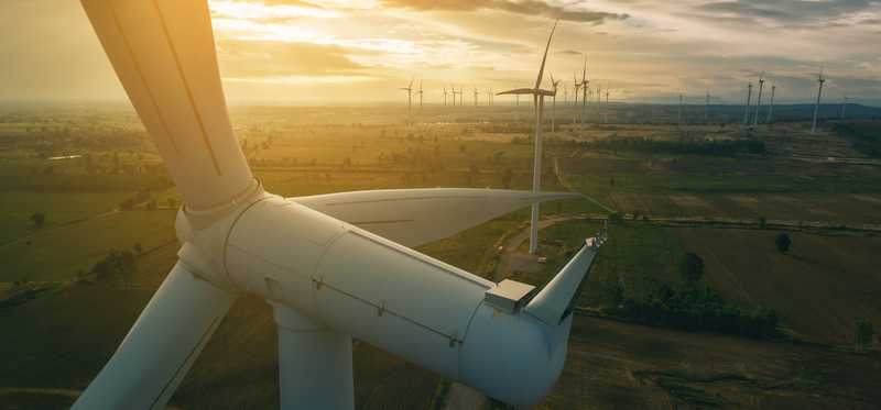 A wind turbine with the sun shining brightly.