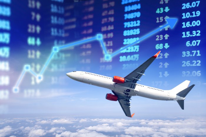 Airplane flying with stock market numbers and a chart in background.