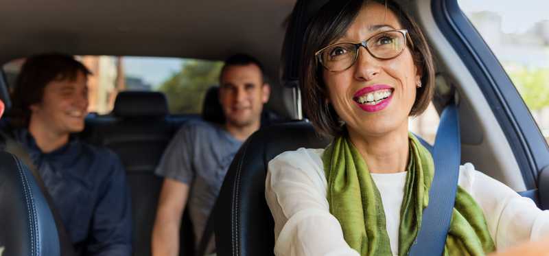 An Uber driver transporting two passengers in her car.