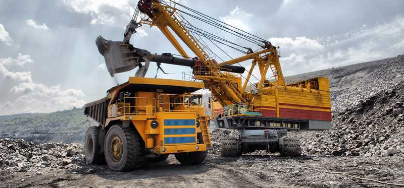 An excavator loading a dump truck in an open-pit mine.