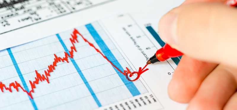 An investor circling a trough in the stock market with a red felt pen.