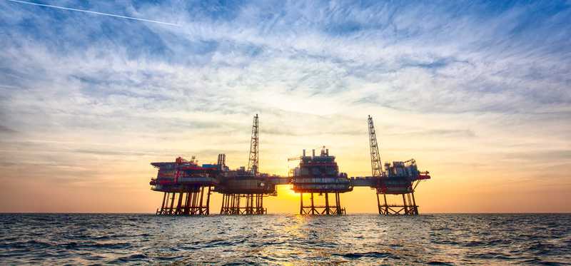 An offshore oil production platform at sunset.