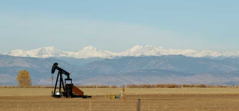 An oil pumpjack in with the Colorado Mountains in the background.