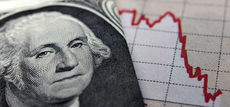 An up-close view of George Washington’s face on the one dollar bill next to a plunging chart