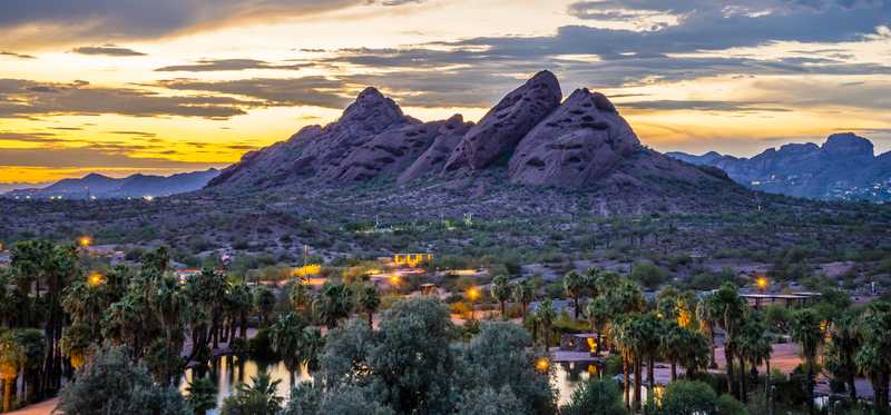 View of mountainous skyline rising above the shadowed city beneath it at dusk in Arizona.