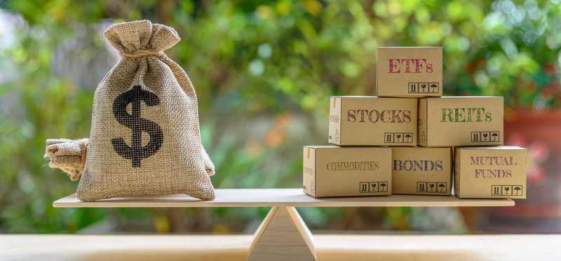 Burlap sack of money balanced on a seesaw versus stocks, bonds, and more.