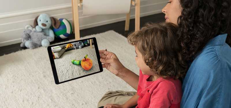 A mother and child using augmented reality on a tablet in their living room