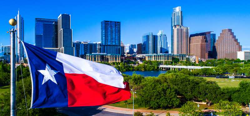 The beautiful Texas state flag flying over Austin, Texas, skyline.