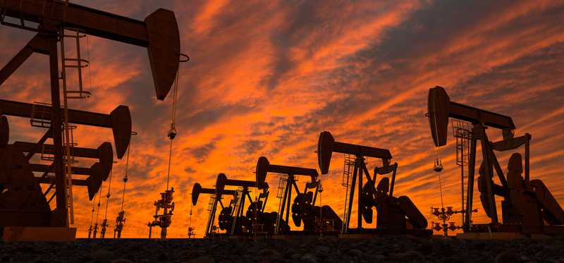 Several oil pumps in a row at dusk