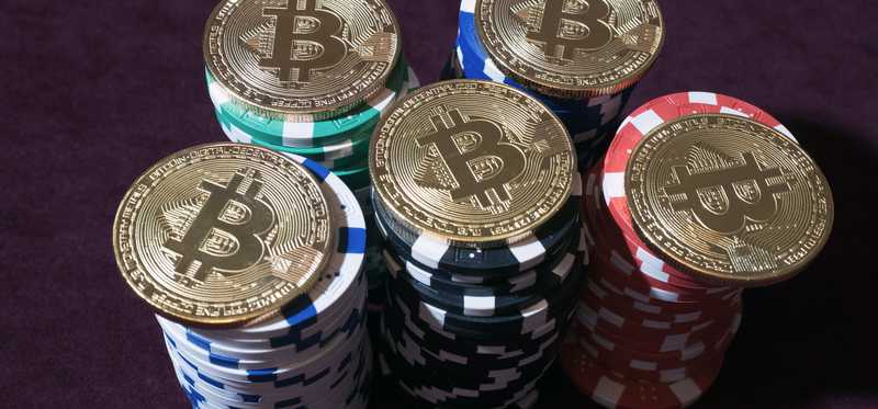 Physical gold coins marked with Bs on top of stacks of poker chips.