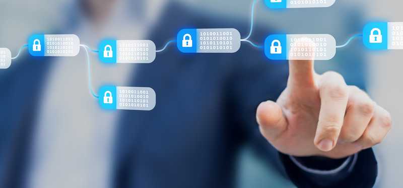 A person touching an individual encrypted block that's part of a blockchain on a digital screen.