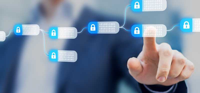 A person touching an individual encrypted block that's part of a blockchain on a digital screen.