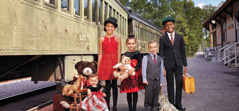 Kids are wearing nice clothes in front of a train