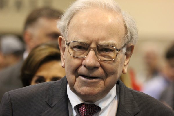 Warren Buffett stands in a room full of people.