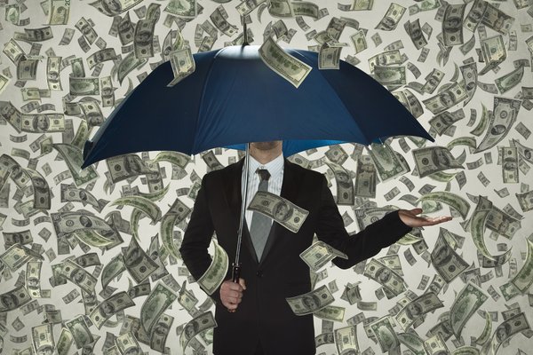 Person holding umbrella as money rains down.
