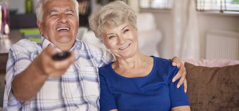Elderly couple watching television together.