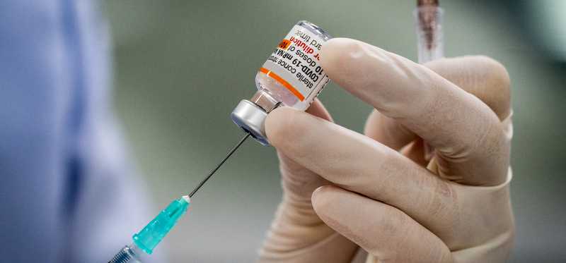 An injection of COVID-19 vaccine being drawn into a syringe.