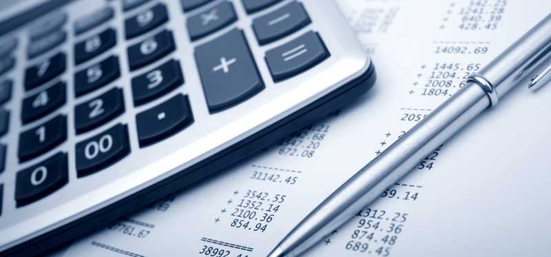 A calculator and pen sit on financial paperwork.