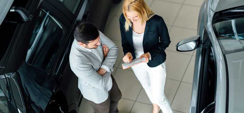 Two people talking between two cars.