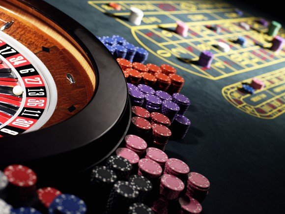 Casino chip son a table next to a roulette wheel.