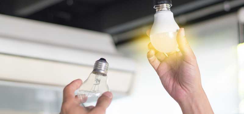 Hand changing out a lightbulb to an LED bulb.