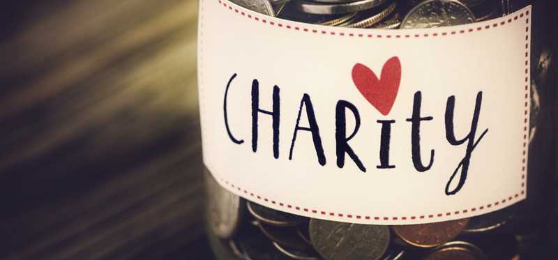 Coins in a glass jar labeled Charity.