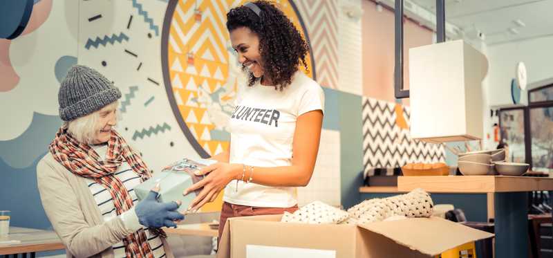 Charity volunteer assisting a client near donation box