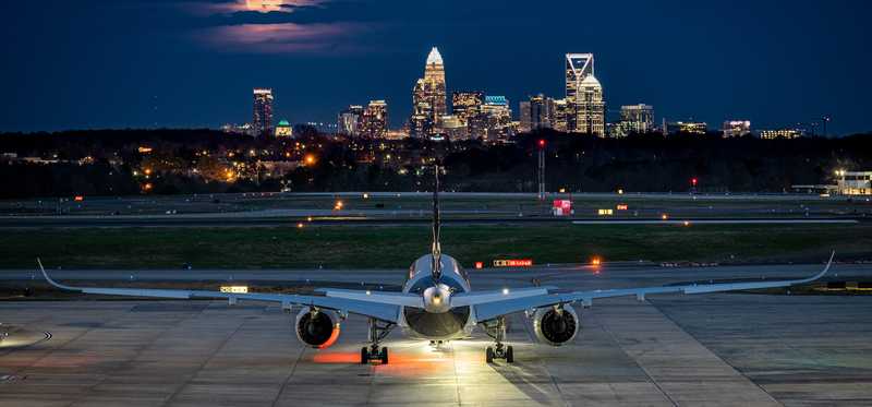 A jetliner lands in Charlotte, North Carolina, with a view of the uptown skyline.