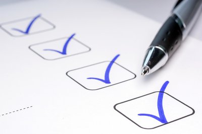 A sheet of paper with a row of boxes being checked off with blue ink pen.